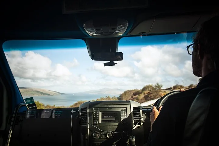Ein Fahrer in einem Fahrzeug mit Blick auf eine Küstenlandschaft